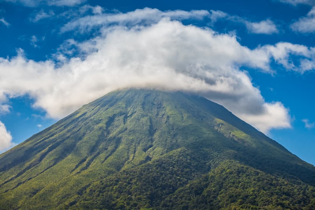 Arenal volcano's forested cone rising into cloud
